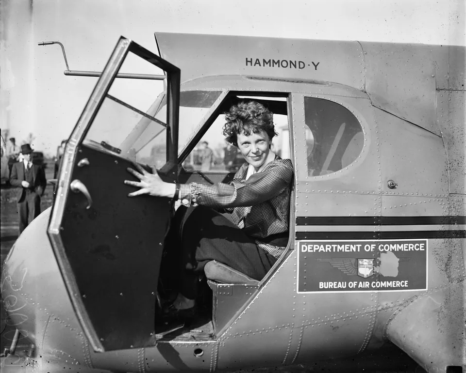 Amelia Earhart sentada a los mandos de una aeronave.